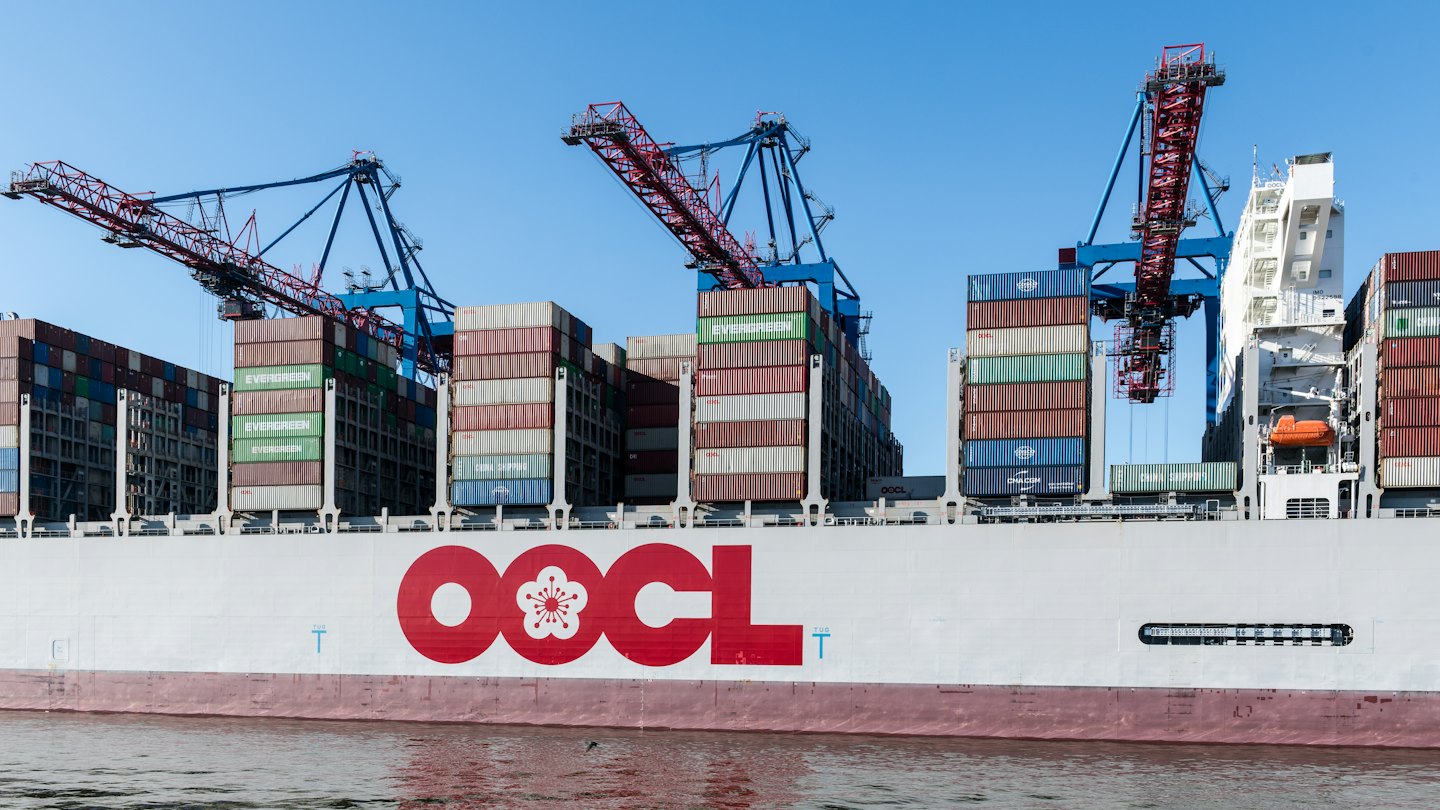 Large cargo ship being loaded by gantry cranes at port.